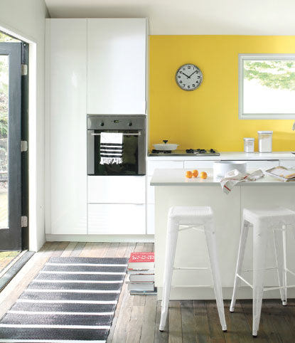 Trendy kitchen with yellow wall and industrial chairs.