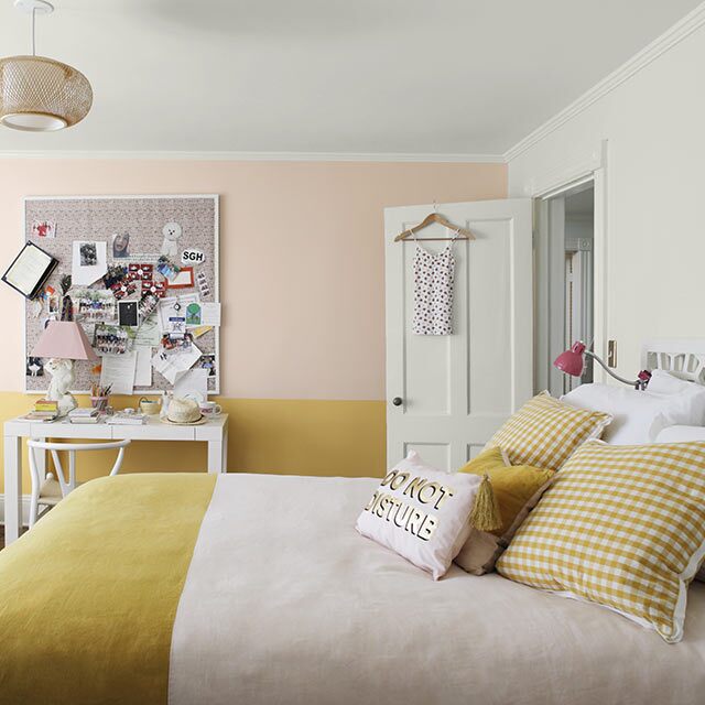 Pink-and-yellow-painted bedroom with beanbag chair, corkboard, white desk and bedspread with two-toned bedding.