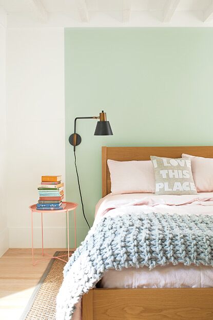 A white bedroom with a green-painted square behind a wooden bed.