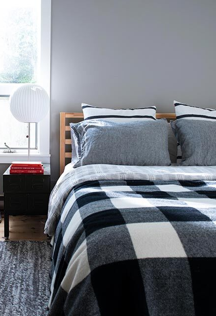 A gray-painted bedroom with white shiplap ceiling and bed with plaid bedding.