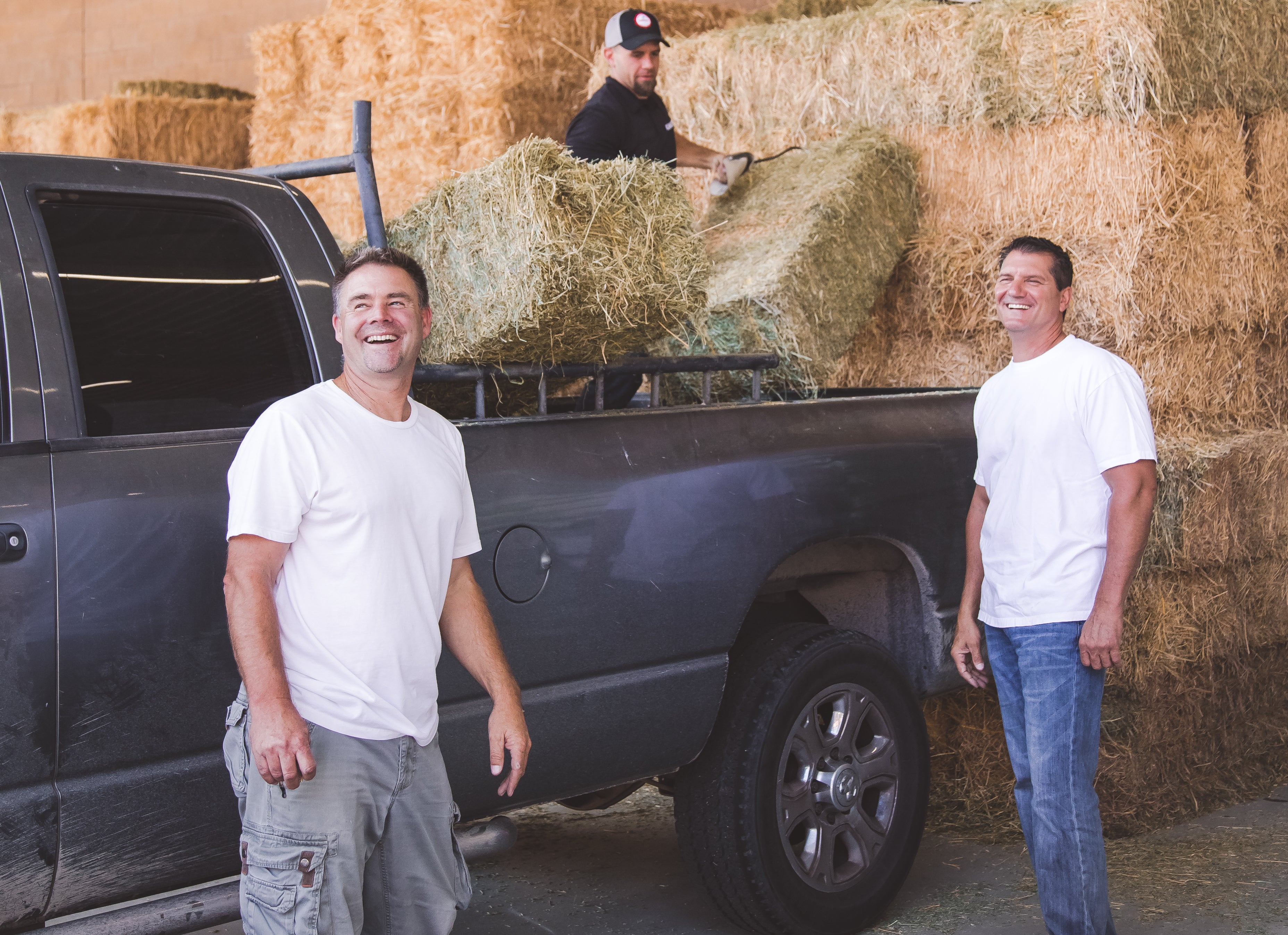 Mike and Ethan standing in front of pickup as hay is being loaded into the back.