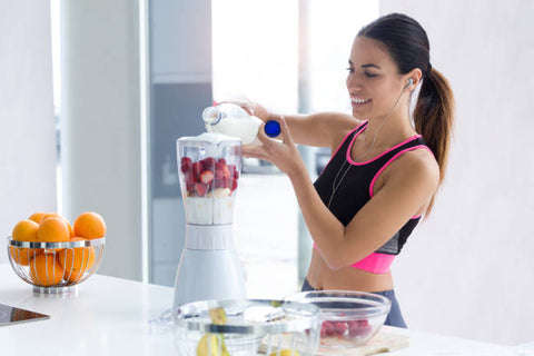 Woman blending strawberries and almond milk 