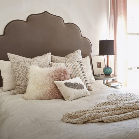 A bed with pillows and a chunky throw.