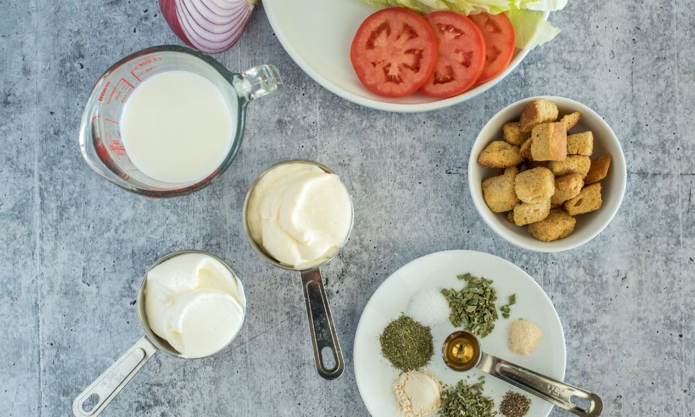 Layout with ingredients for Buttermilk Salad dressing including buttermilk, sour cream and seasonings.