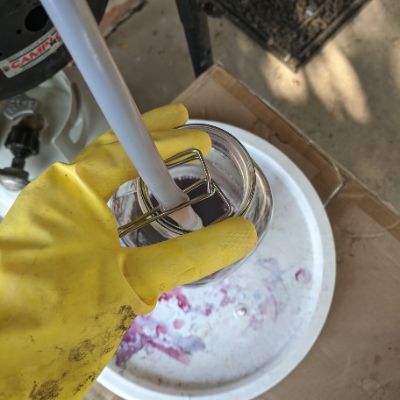 Hand with yellow rubber glove holding tube into mason jar