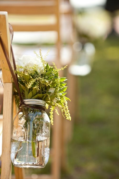 Mason jar with flowers hanging from chair
