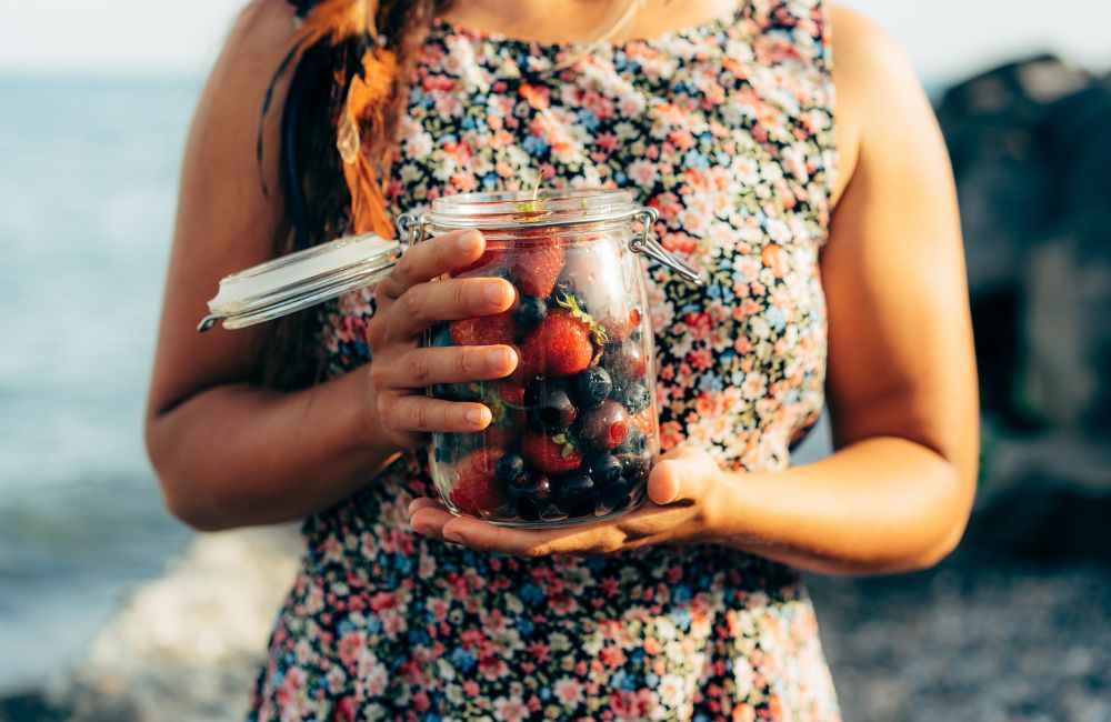 Woman holding strawberries, blueberries and blackberries in jar