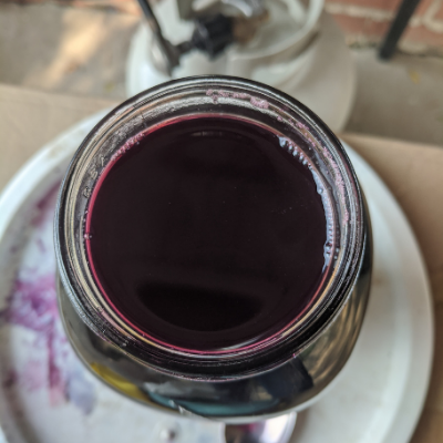 Mason jar full of dark purple grape juice.