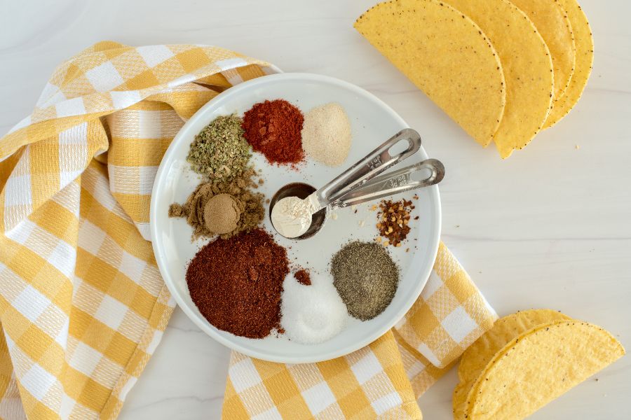 Bowl with piles of various spices.  Bowl is laid over yellow checkered cloth.