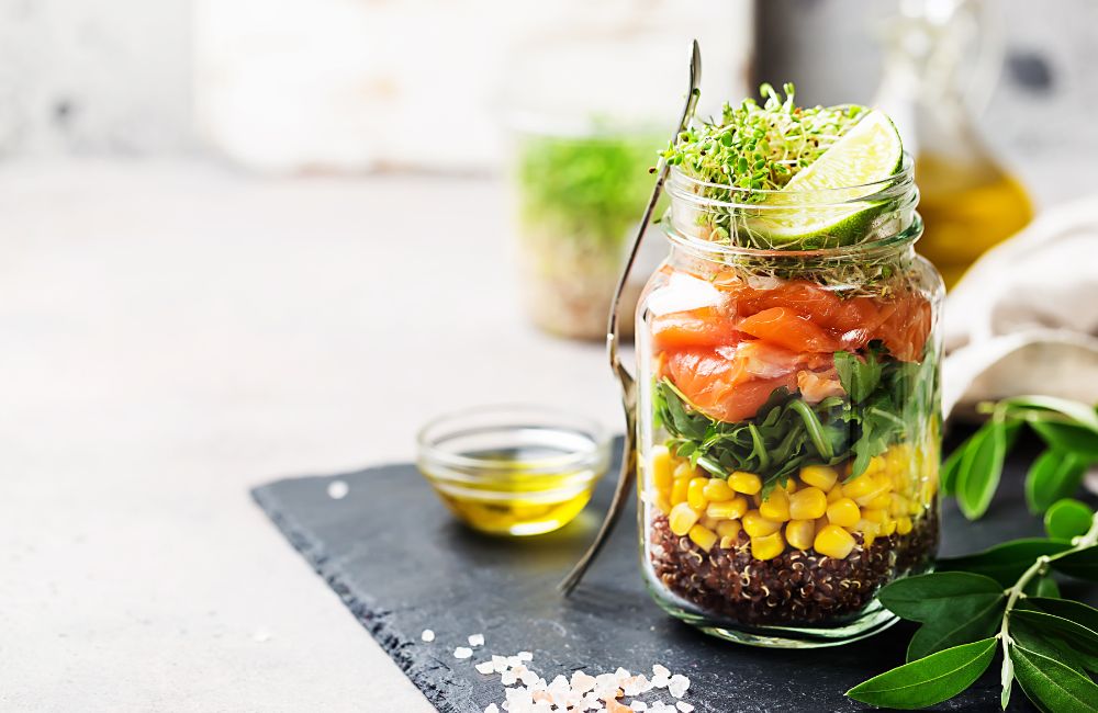 Layered salad in a jar with grains, greens and corn