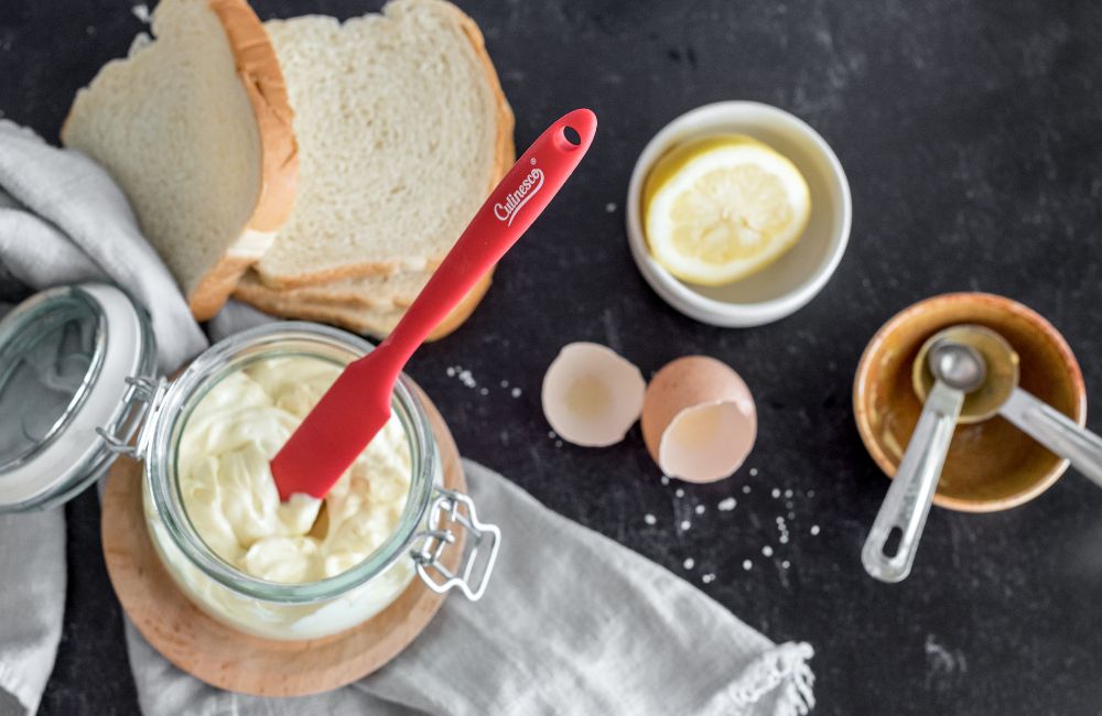 Red jar scraper sticking out of jar of mayo.