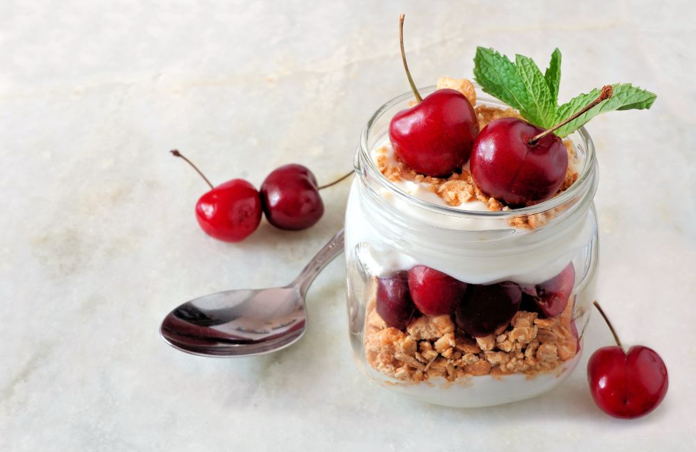 Yogurt, granola and cherries layered in a jar