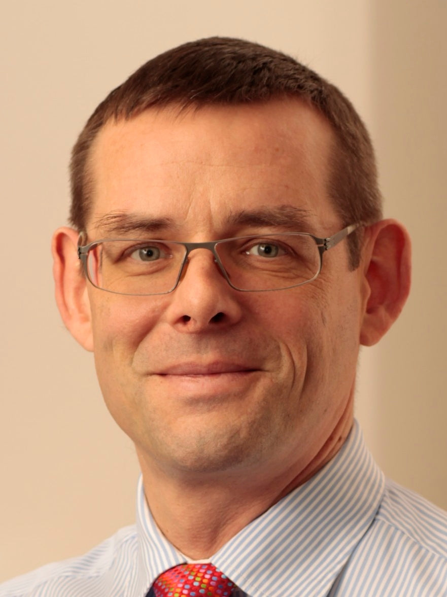 Middle-aged man in glasses with striped shirt and patterned tie.