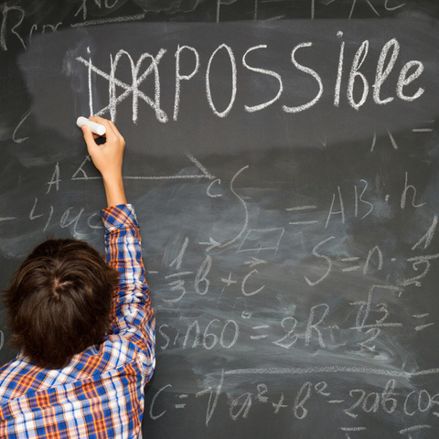Child writing 'Possible' on a chalk board
