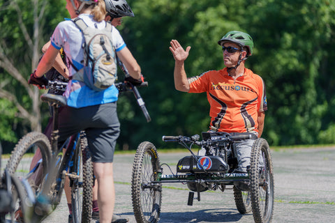 An adaptive athlete talking to a cyclist