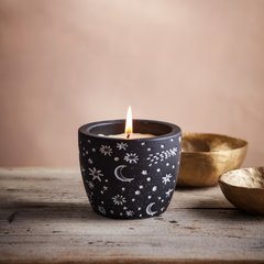 Lit Orange & Cinnamon Celestial pot with white stars on a black background