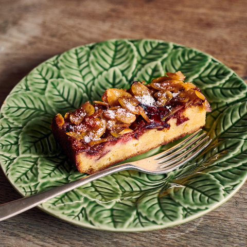 Purple Plum Frangipane slice on a green plate featuring leafy designs with a fork