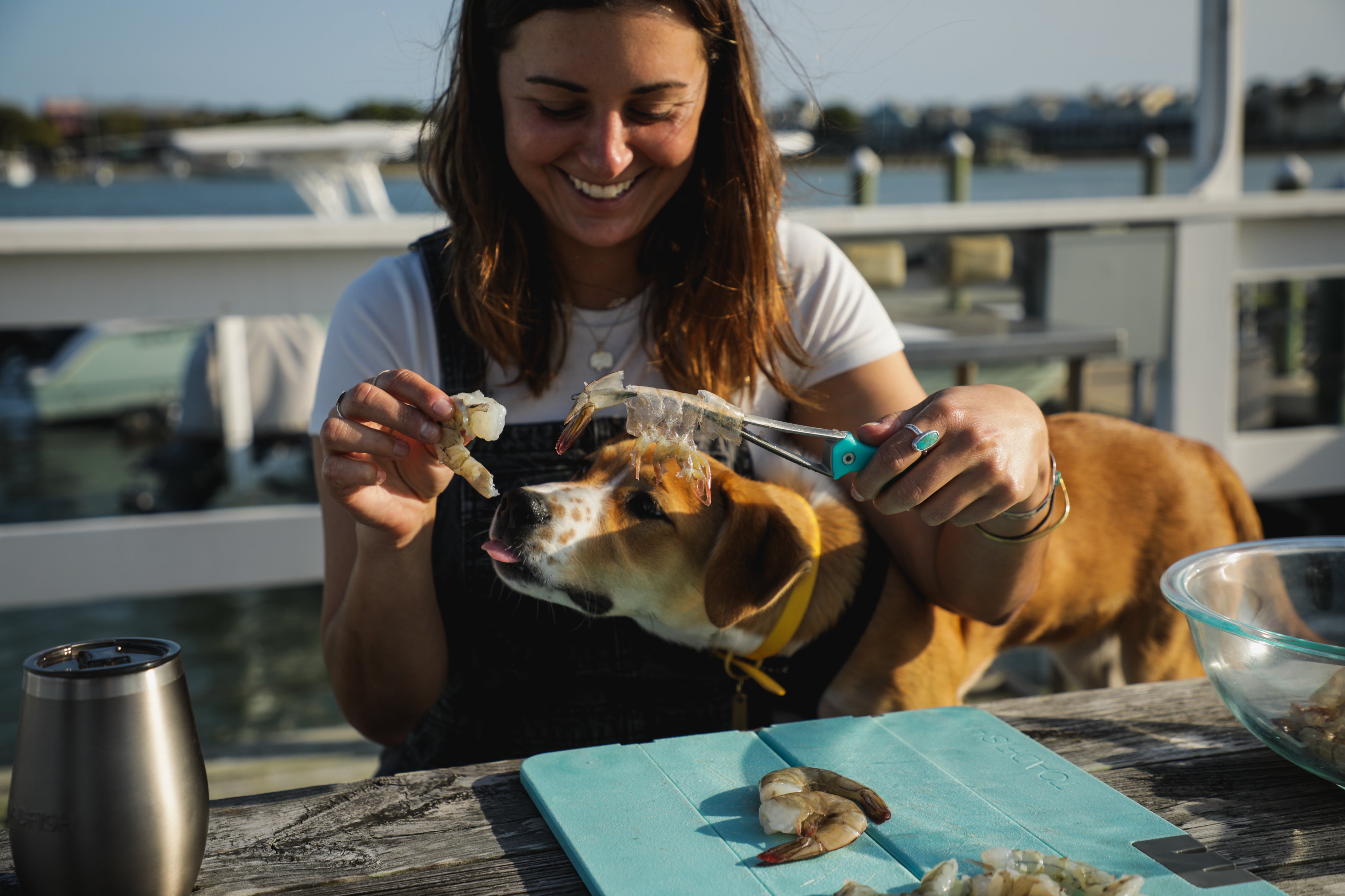 Smiling women peeling shrimp with dog trying to lick the shrimp