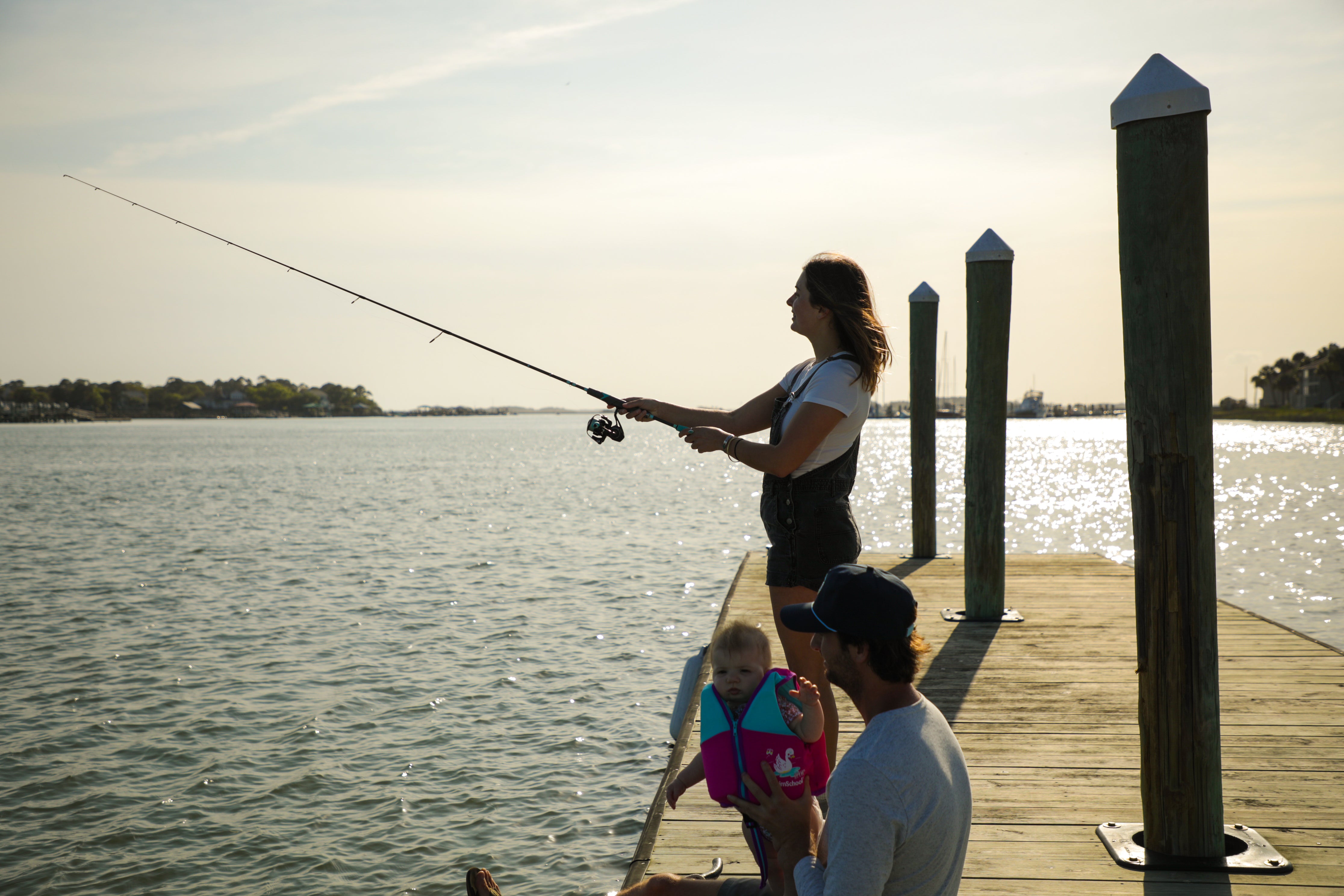 Women holding fishing rod on dock with dad and child
