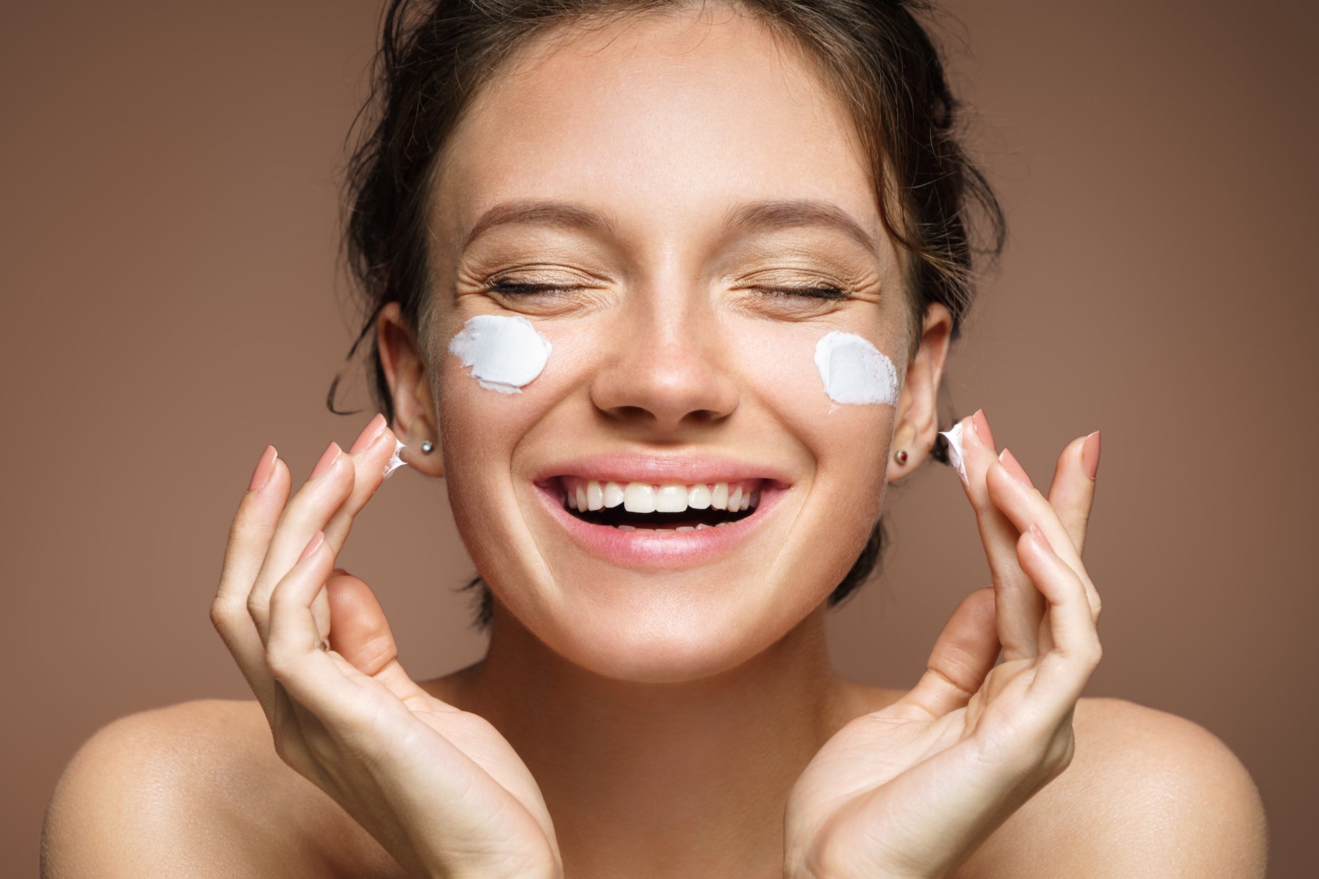 Woman smiling while applying face cream