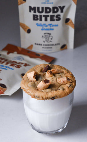 Chocolate chip cookies topped with Muddy Bites waffle cone snacks and a glass of milk