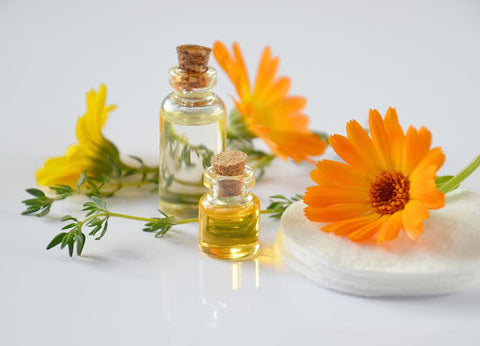 two bottles of essential oils amid yellow flowers