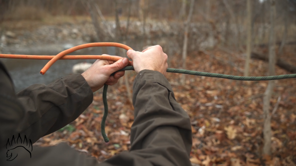 Starting a double fisherman's bend by coiling the orange rope backward over the green rope