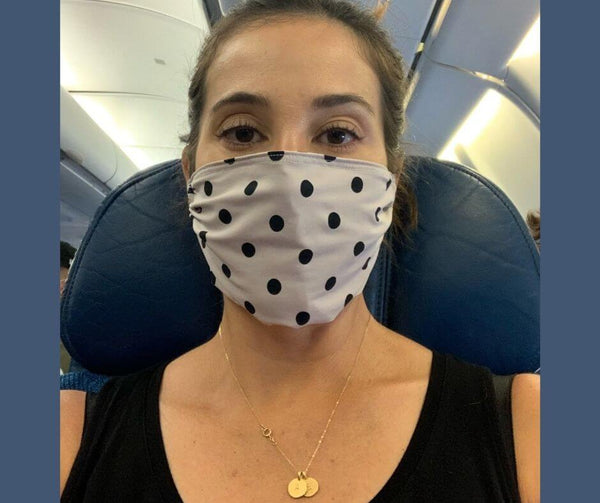 Woman on airplane wearing a Heliades UV sun protection face mask in UPF 50+ ballet pink polka dotted fabric