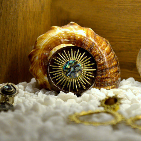 Wood Ear Plug with Shell and Gold Sun Ray Detailing, photographed on a shell