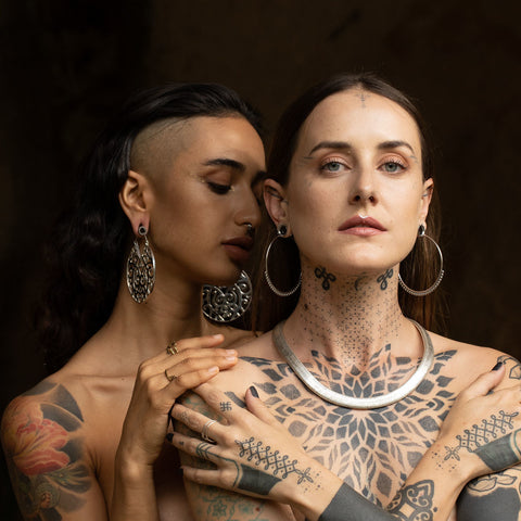 Two models wearing large silver hoop earrings by Tribalik