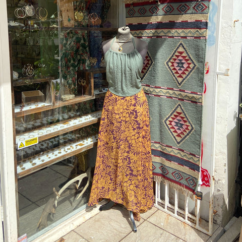 Outside of Tribalik, mannequin wearing a yellow/purple patterned skirt with a green crop top