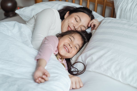 Mother and daughter in bed smiling