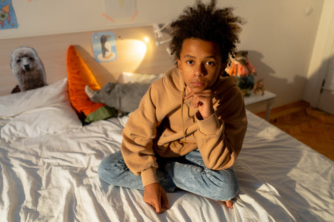 Middle school student sitting on bed and looking at camera