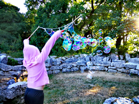 A 9 year old boy using our bubble wands to make a stream of multi-coloured bubbles in the sunlight on Anglesey, North Wales