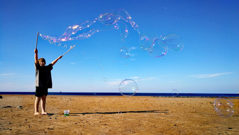 Child, Ziggy, playing with Dr Zigs Eco Bubbles on a Beach with Blue Sky