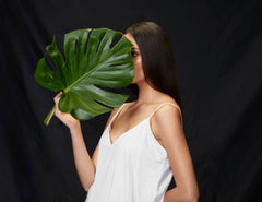 Model holding leaf in hand wearing ALIGNe white skinny strap dress