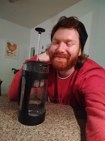 A selfie of a ver happy bearded gentleman and the object of his affection: an Espro french press