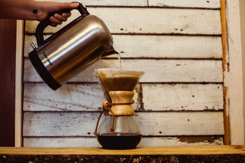 Coffee is brewing through a cloth filter in a chemex using a chrom hot water kettle.