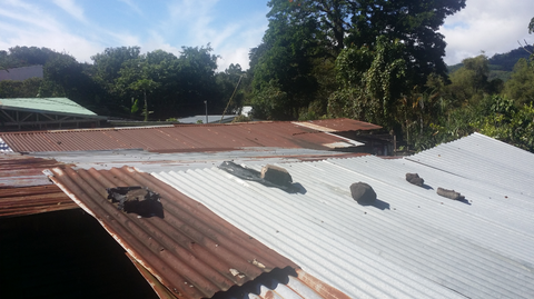 Most coffee pickers live in small homes with tin roofs. Here you see rocks placed so that the roof does not blow off during storms. Elba paid to have new roofing installed for a family of coffee pickers in El Salvador.