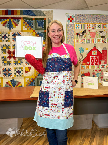 Christy wearing the Red, White, and Bloom Apron while holding the June Stash Box