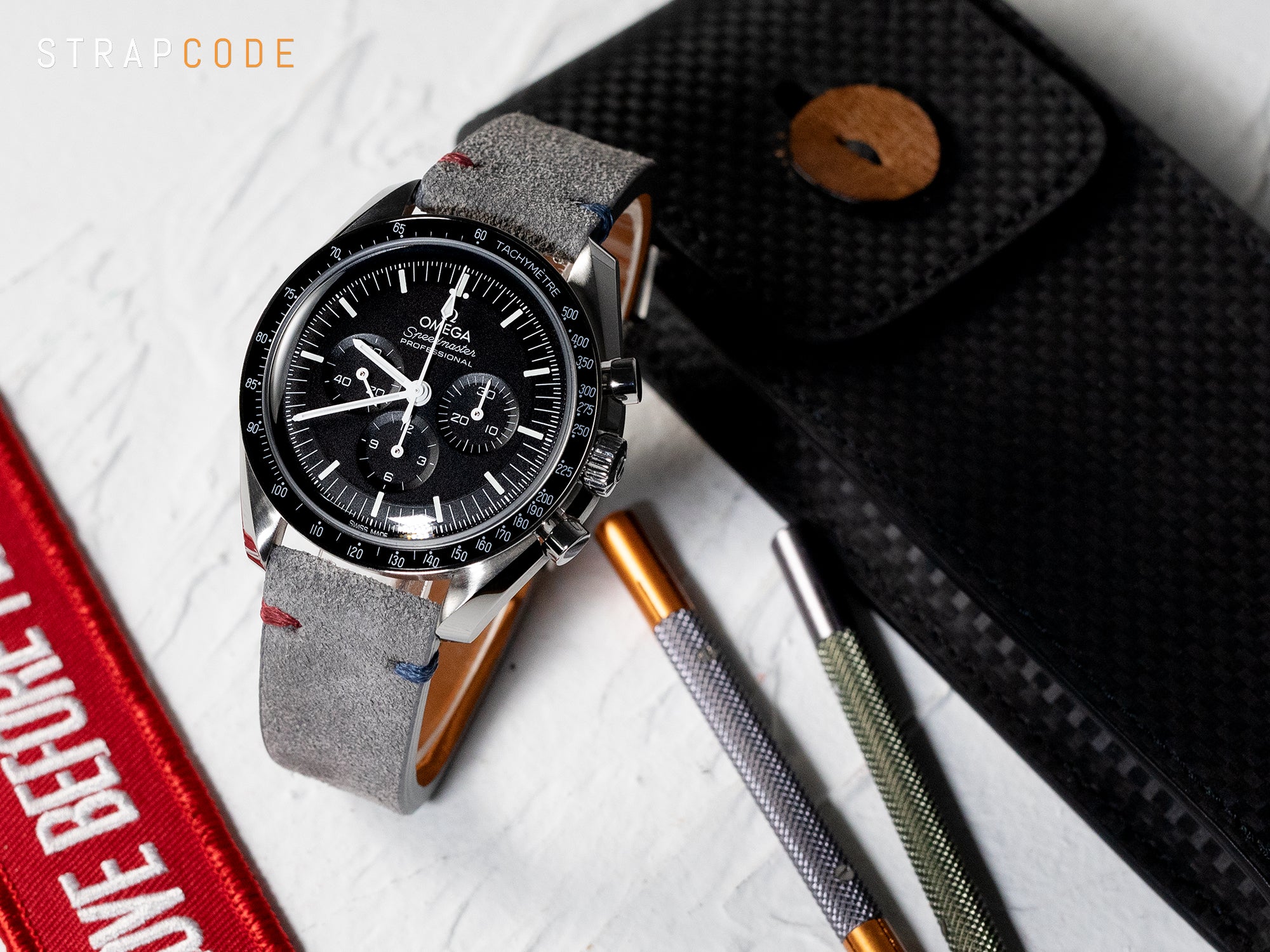 Omega Speedmaster paired with a Grey suede watch strap by Strapcode