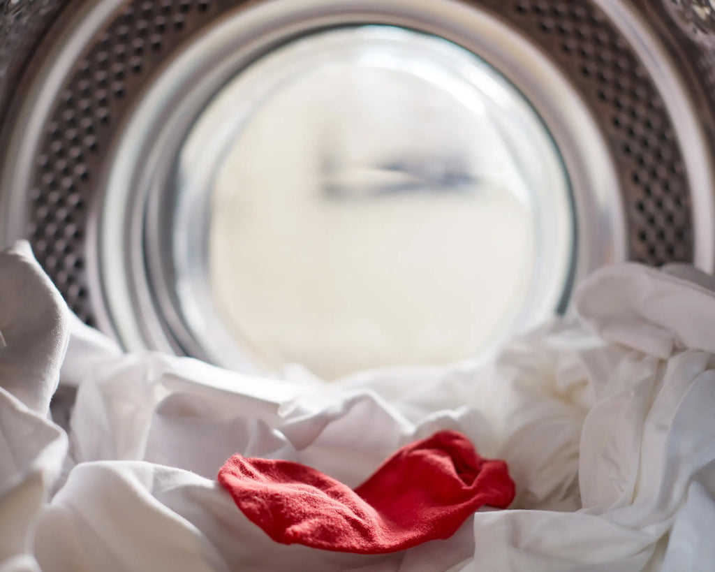 a red sock on top of white linens inside a laundry machine