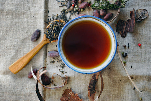 Kopp med Dianhong-te med løse teblader og kakaobønner rundt