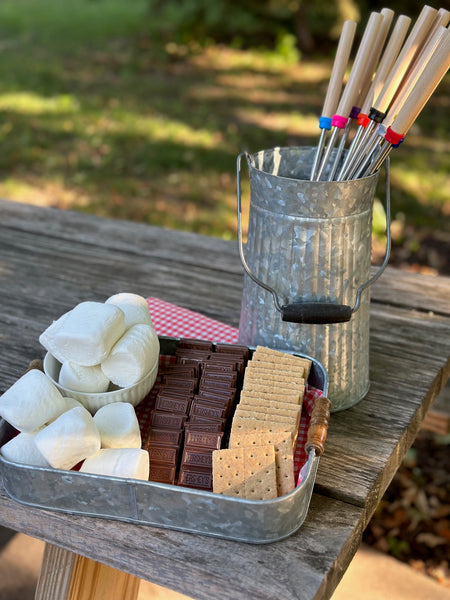 galvanized tray with s'mores items and galvanized bucket holding fire skewers for making s'mores