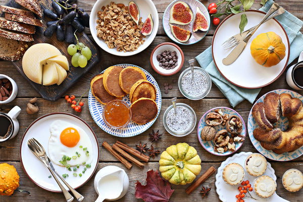 Top down view of various plated breakfast and brunch style foods on a rustic wooden table