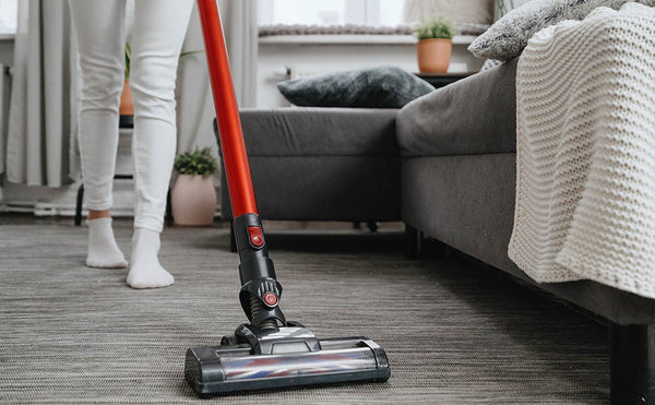 woman holding a vacuum cleaning a rug