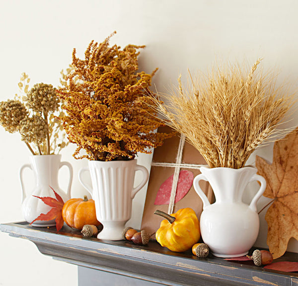 mantel decorated with vases full of fall foliage and pumpkins