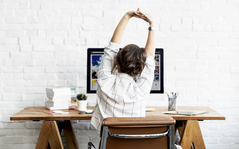 Woman sitting at office desk stretching 