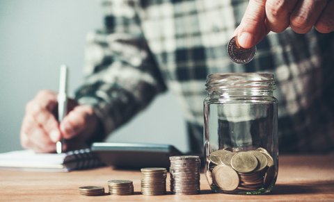 Man putting money in a coin bank