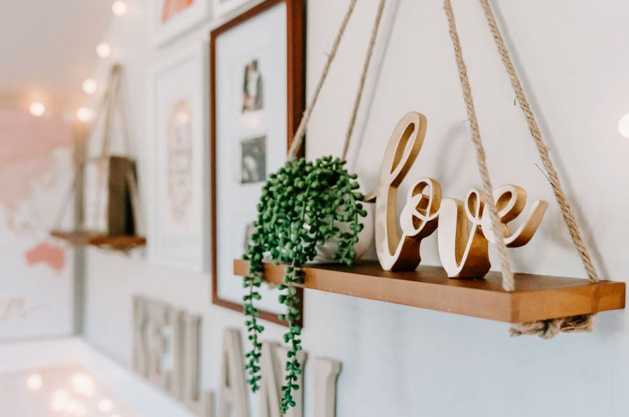 Decorative wall shelf with potted plant and wooden love sign with information on how to properly hang photos on your wall